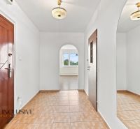 A hallway in a 2-room apartment with a wooden decor floor and a mirror on the wall.