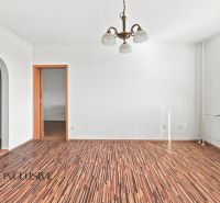 A room in a 2-room apartment with a wooden decor floor and a chandelier.