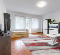 Living room in a 3-room apartment with a wooden decor floor, light furniture, and decorations.