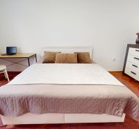 Bedroom in a 3-room apartment with a bed, television, and wooden floor decor.