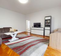 Living room in a 3-room apartment with a wooden decor floor and a comfortable sofa.