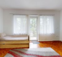 A room in a three-room apartment with a wooden decor floor and a large window.
