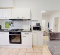 A kitchen in a 3-room apartment with ceramic tiles and a white kitchen unit.