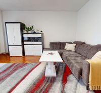 Living room in a 3-room apartment with a corner sofa, white table, and wooden decor flooring.