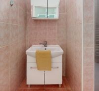 Bathroom in a 3-room apartment, pink tiles, a sink with a mirror and a yellow towel.