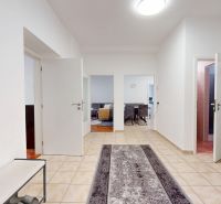 A hallway in a 3-room apartment with tiles and open doors to the rooms.