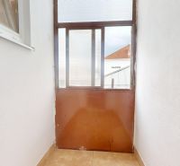 A narrow balcony in a 3-room apartment with white walls and brown doors.