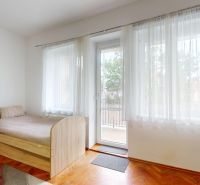 A bright room in a 3-room apartment with a bed and a wooden decor floor.