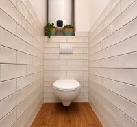 Bathroom in a 2-room apartment with white tiles and a floor with a wooden decor.