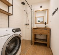 Bathroom in a 2-room apartment, washing machine, shower, sink, floor with wood decor.