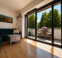 2-room apartment with wood-decor flooring, a balcony, and a sofa by the table.
