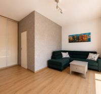 A bright living room with a corner sofa and a wooden decor floor in a 2-room apartment.