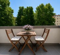 Wooden table and chairs with flowers on the terrace of a 2-room apartment in Banská Bystrica.