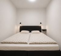 Bedroom in a 2-room apartment with a simple double bed and white bedding.