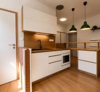 A kitchen with wooden decor in a 2-room apartment, kitchen unit with a black sink.