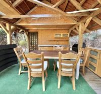The gazebo of a family house in Mojš with wooden furniture and a green carpet.