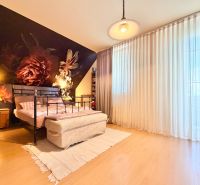 A bedroom with a dark floral motif, a metal bed, and a floor with a wooden decor.