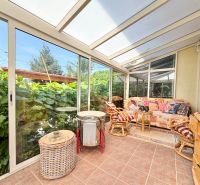 A winter garden in a family house with comfortable seating and a view of the garden.