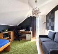 A room with a desk, sofa, bed, and acoustic panels in a family house.