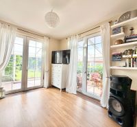 Living room in a family house with white curtains, shelves, and a floor with a wood decor.