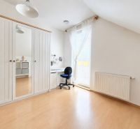 A brightly lit room in a family house with a wooden decor floor, a wardrobe, and a desk.