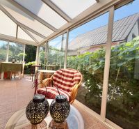 A glazed terrace with comfortable armchairs and a table in a family house.