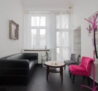Commercial space with a black sofa, colorful chairs and a table, bright atmosphere.