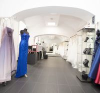 Commercial premises with displayed evening and wedding dresses, wooden decor flooring.