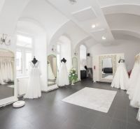 Commercial space with luxury wedding dresses and large mirrors, elegant lighting fixtures.