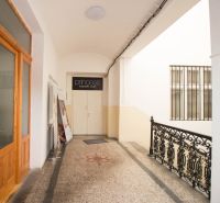 A corridor with commercial spaces with metal railings and white walls.