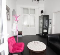 Commercial space with a black chandelier, colorful chairs, and a glass display case.