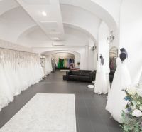 Wedding dress and black couch in a commercial space with arched ceilings.