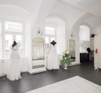 Commercial space with elegant wedding dresses, mirrors, and a black floor with decor.