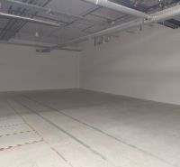 Empty commercial spaces with ceiling pipes and concrete floor.