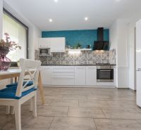 A kitchen in a 2-room apartment with white furniture and decorative cladding.