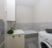 Bathroom of a 2-room apartment with a shower, sink, and washing machine.