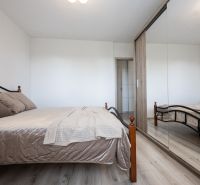 Bedroom in a 2-room apartment with a bed and a mirrored wardrobe, floor with wood decor.