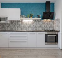 A kitchen in a 2-room apartment with white furniture and tiled backsplash.