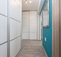 A narrow hallway in a 2-room apartment with white doors and a mirror.