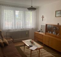 Living room in a 3-room apartment with a sofa, display cabinet, and wooden decor flooring.