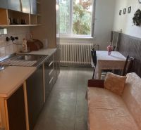A kitchen in a 3-room apartment with a wooden decor floor and a sofa.