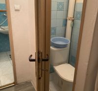 A toilet with light tiles and blue tiles in a 3-room apartment.