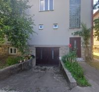 A family house in Rožňava with a garage and a garden surrounded by greenery.