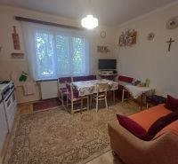 A kitchen in a family house with a gas stove, a sofa, and a television on the wall.