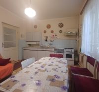 A kitchen in a family house with decorative plates on the wall, a dining table, and a couch.