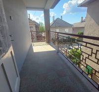 A balcony of a family house in Rožňava with a view of other houses and the sky.