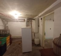 Basement storage in a family house with pipes and plastic crates.