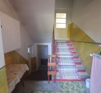 Interior of a family house with a staircase, carpets, and a table.