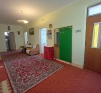 A hallway in a family house with a carpet, comfortable sofas, and a built-in coat rack.