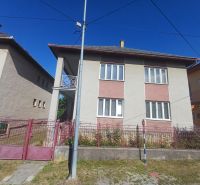 A family house in Rožňava with a brick fence, located between two other houses.